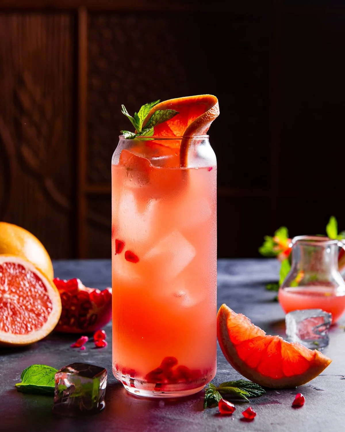 Grapefruit and pomegranate cocktail on a dark wooden table.
