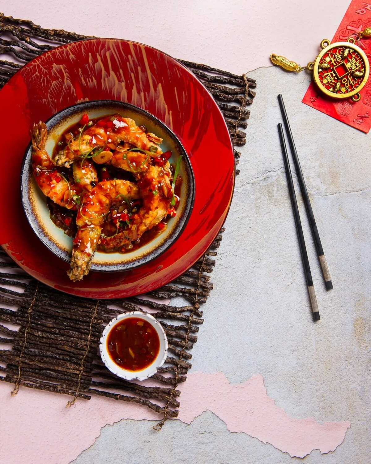 Tiger prawns in spicy Sichuan sauce on a red plate.