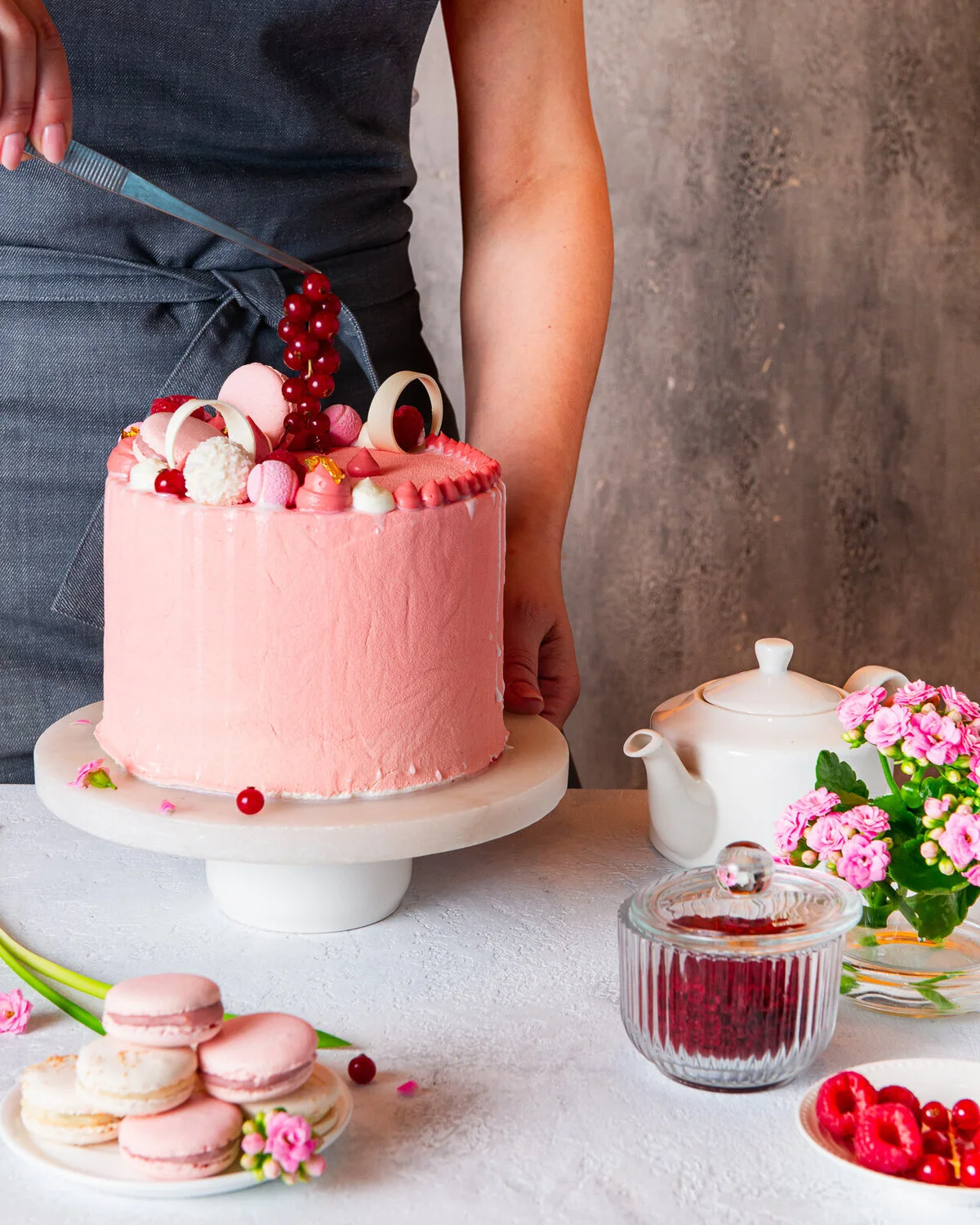 Pink celebration cake with berries and white decorations.