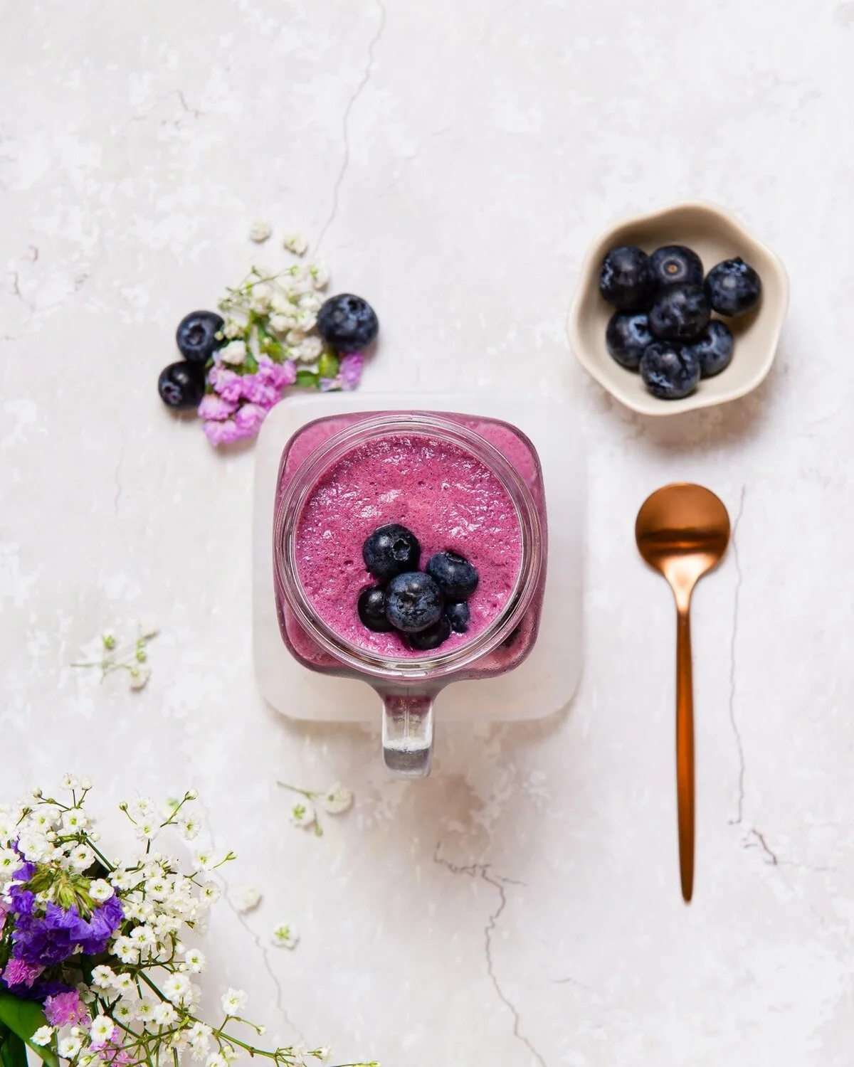 Overhead blueberry milkshake with fresh blueberries and a spoon.