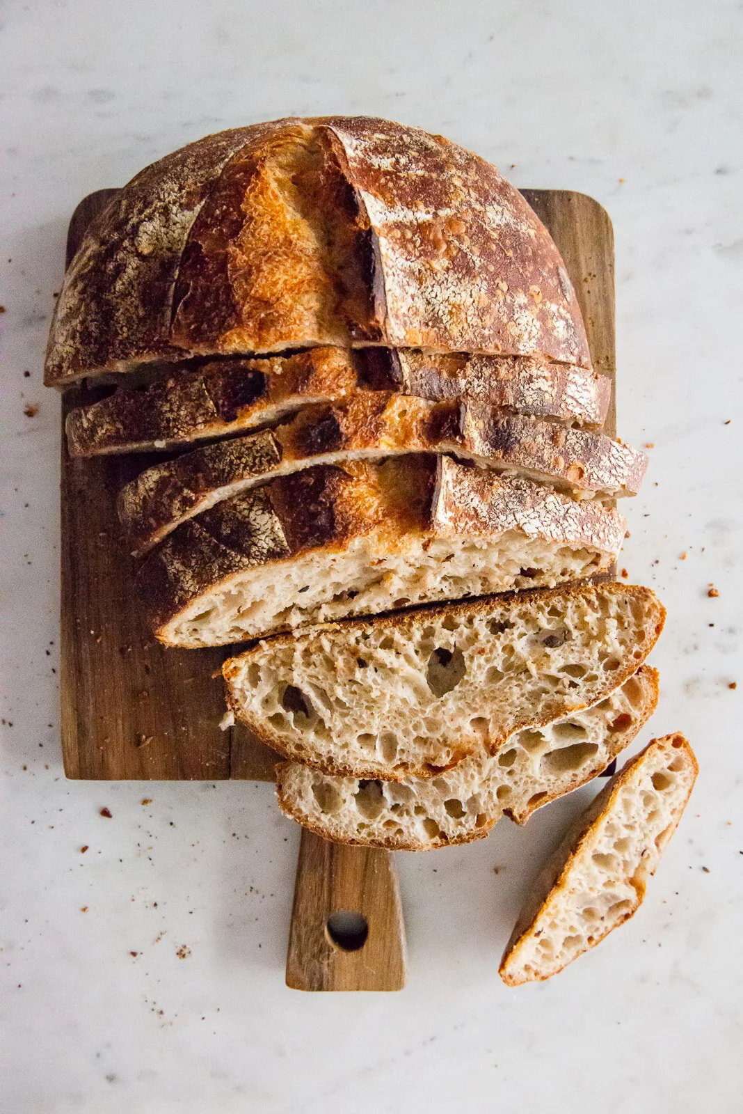 Sliced rustic bread arranged on a pale surface.