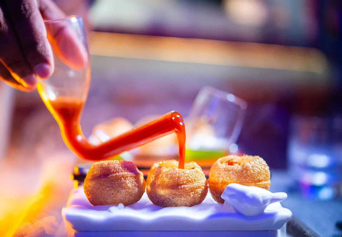 Orange sauce poured over golden bites on a white plate.