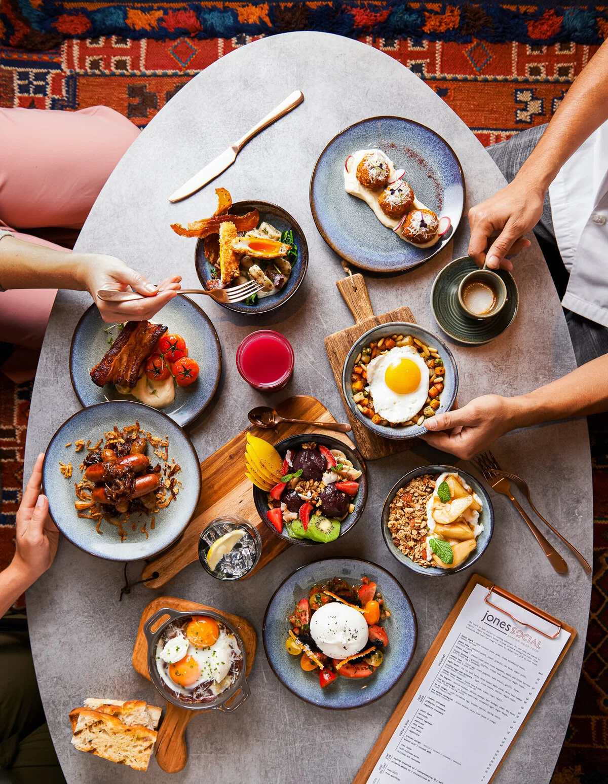Overhead restaurant spread with plates of food and drinks on marble tables.