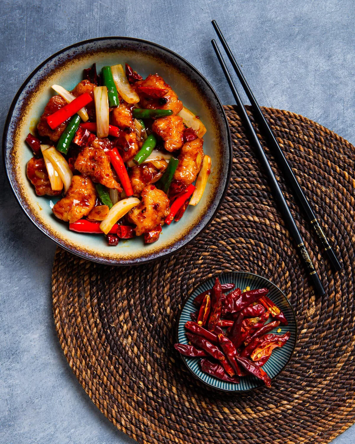 Wok-fried grouper in spicy Sichuan sauce beside chopsticks.