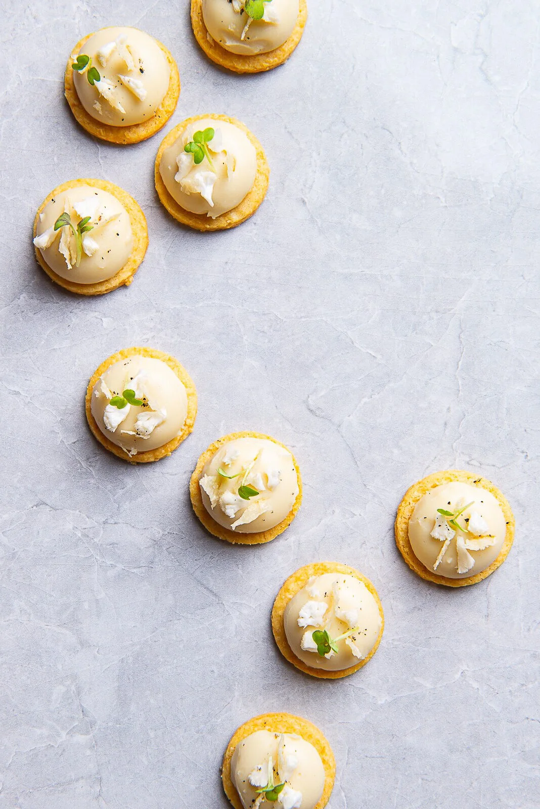 Small round canapés arranged diagonally on a white surface.