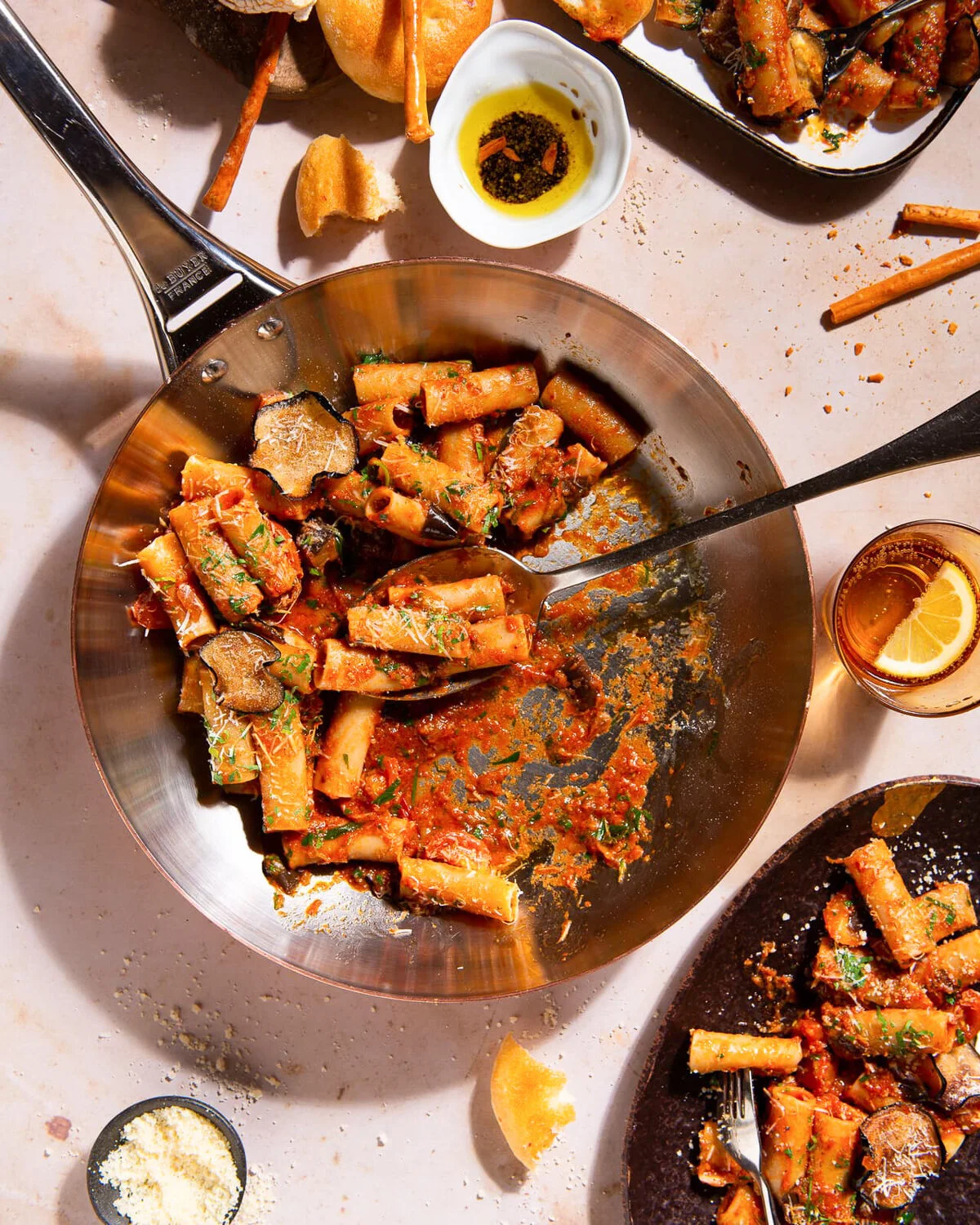 Overhead pasta spread with serving pans and small side dishes.