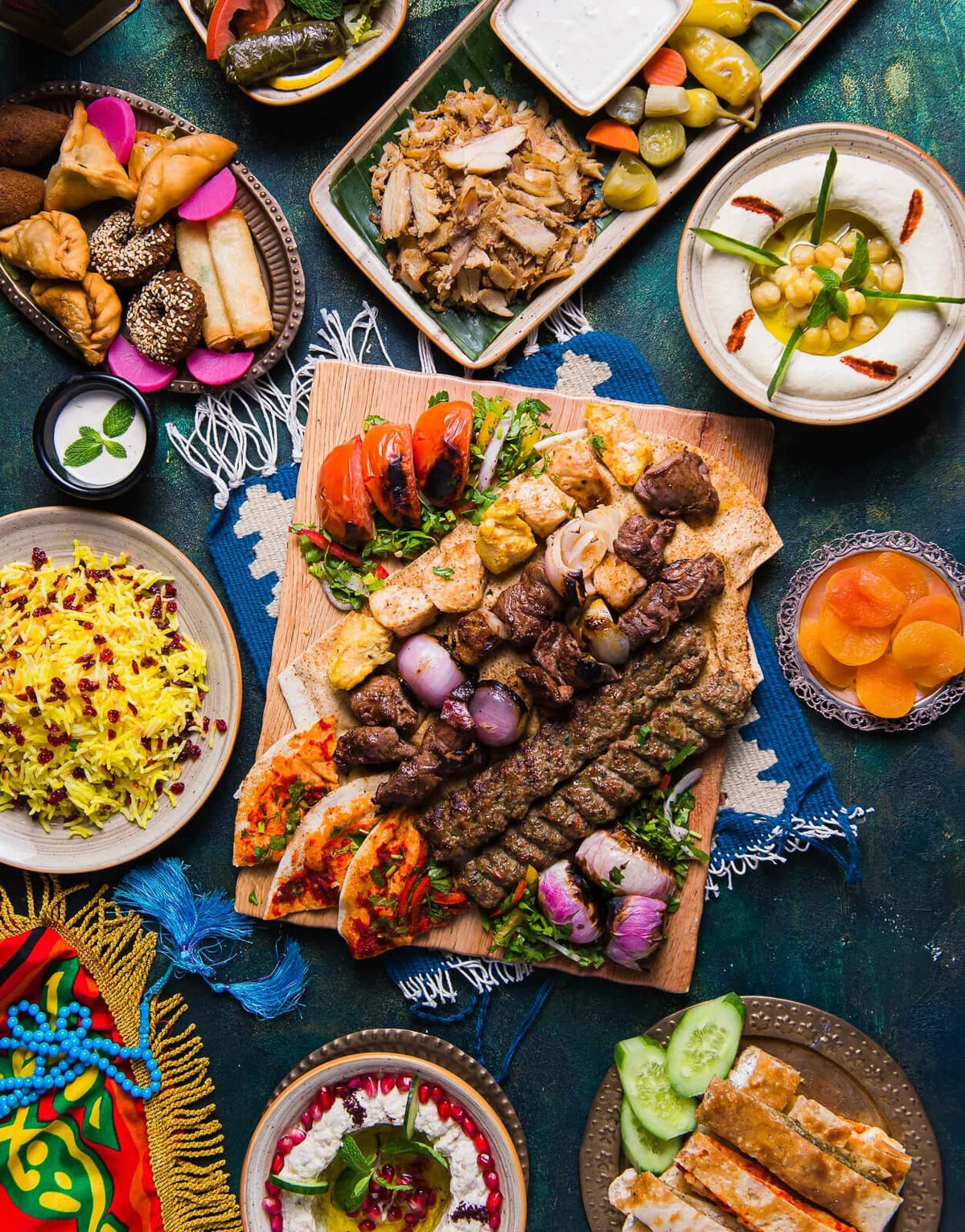 Overhead feast with grilled meats, rice and colorful side dishes.