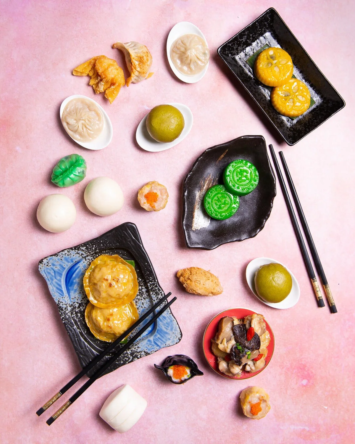 Overhead spread of dumplings and small dishes on a pink table.