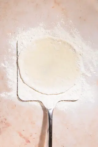 Animated pizza preparation on a pale surface.