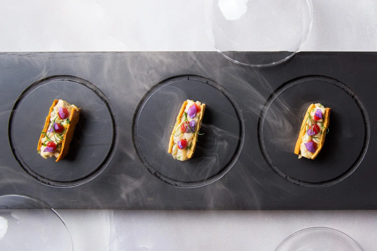 Three small sandwiches on dark round plates.