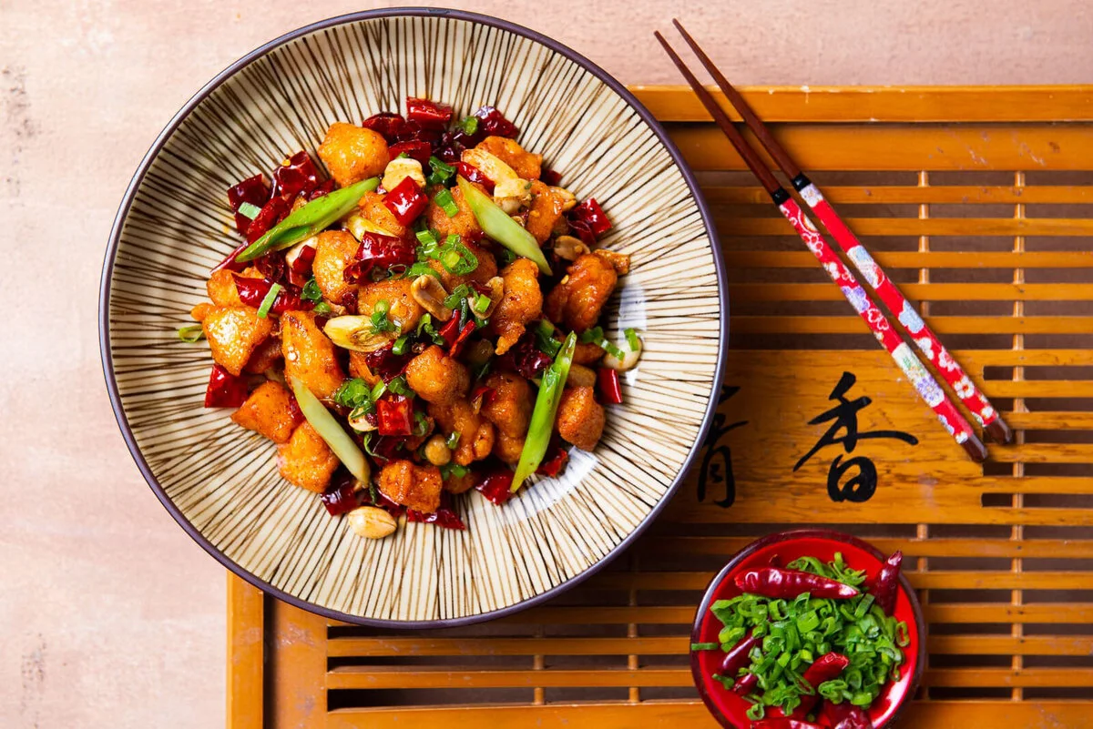 Fried chicken with dried chilies and Sichuan pepper on a patterned plate.
