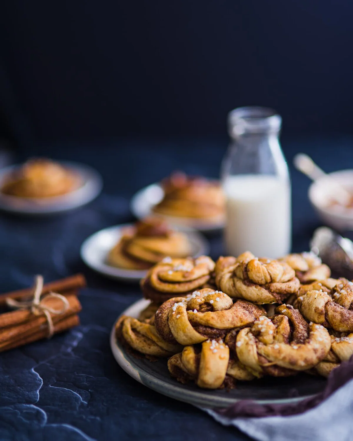 Swedish cinnamon buns beside a bottle and glass of milk.