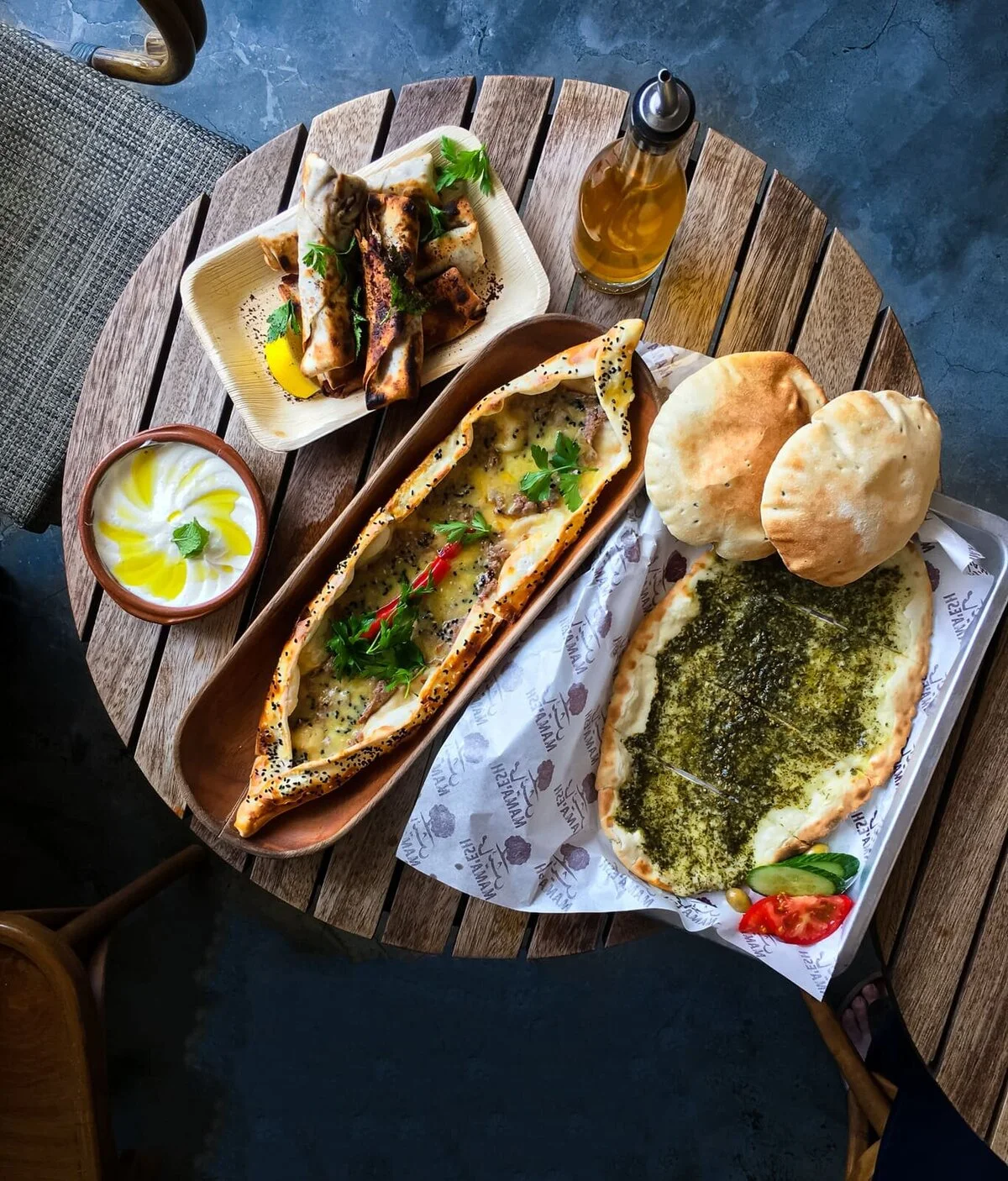 Arabic flatbreads and mezze arranged on a round wooden table.