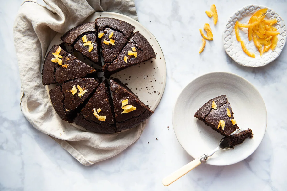 Sliced chocolate orange olive oil cake with scattered chocolate pieces.